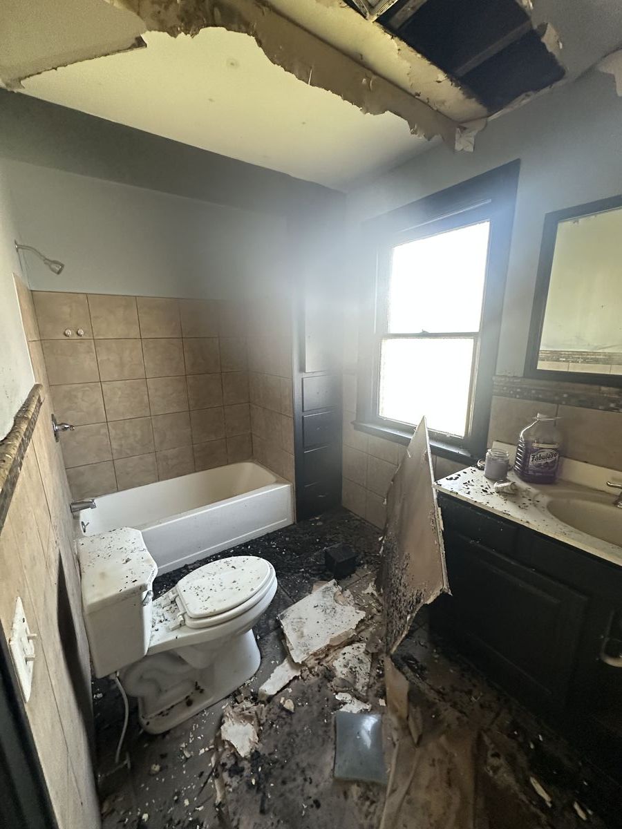 Bathroom destroyed by fire with melted fixtures and collapsed ceiling