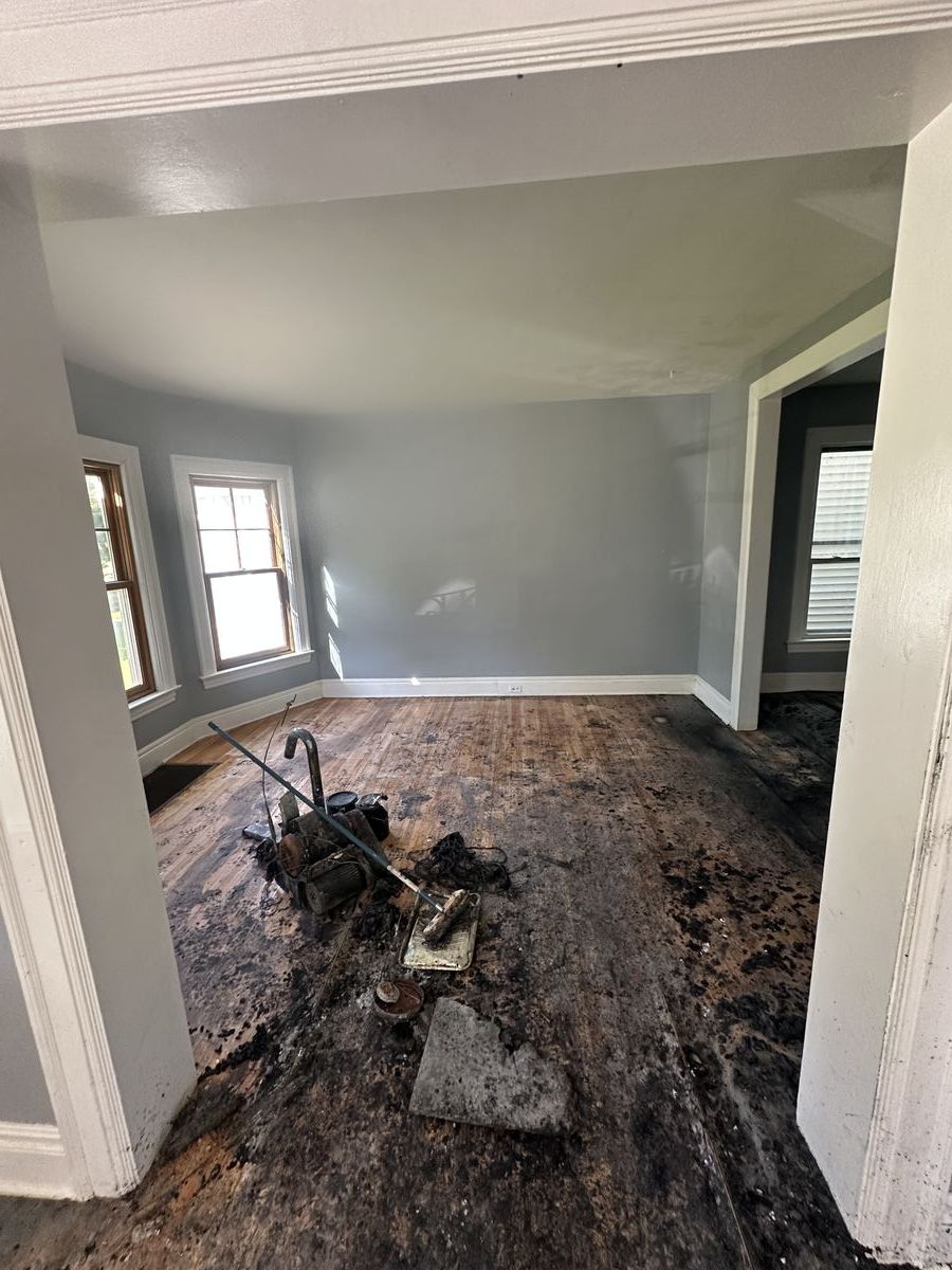 Room with severe fire damage showing charred floor and burnt belongings