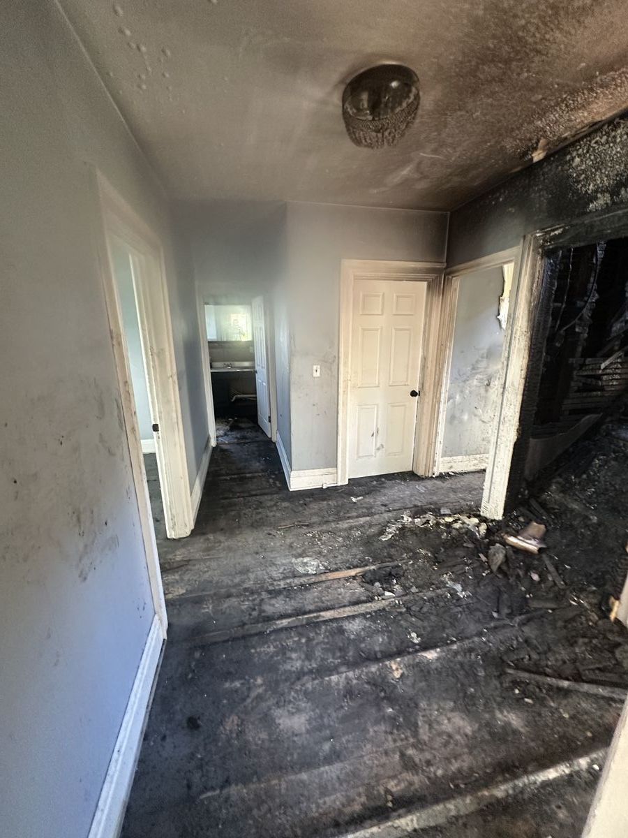 Hallway coated in heavy soot from fire with blackened walls